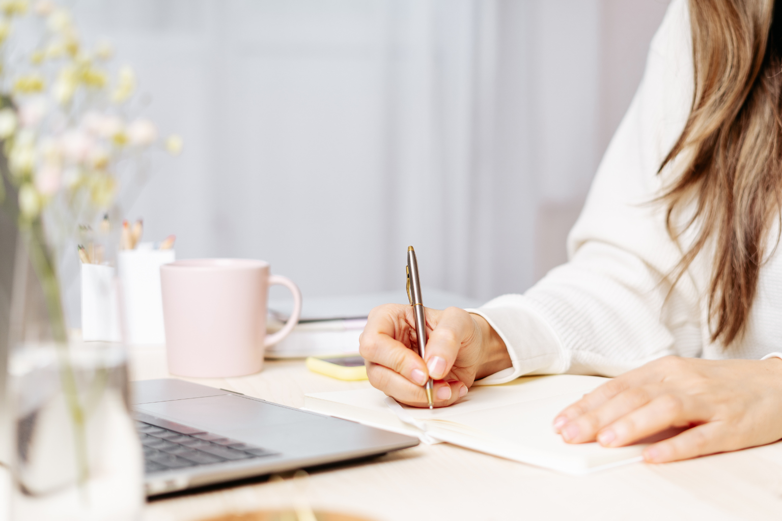 Frau arbeitet im Online-Coaching am Laptop und macht Notizen mit Stift